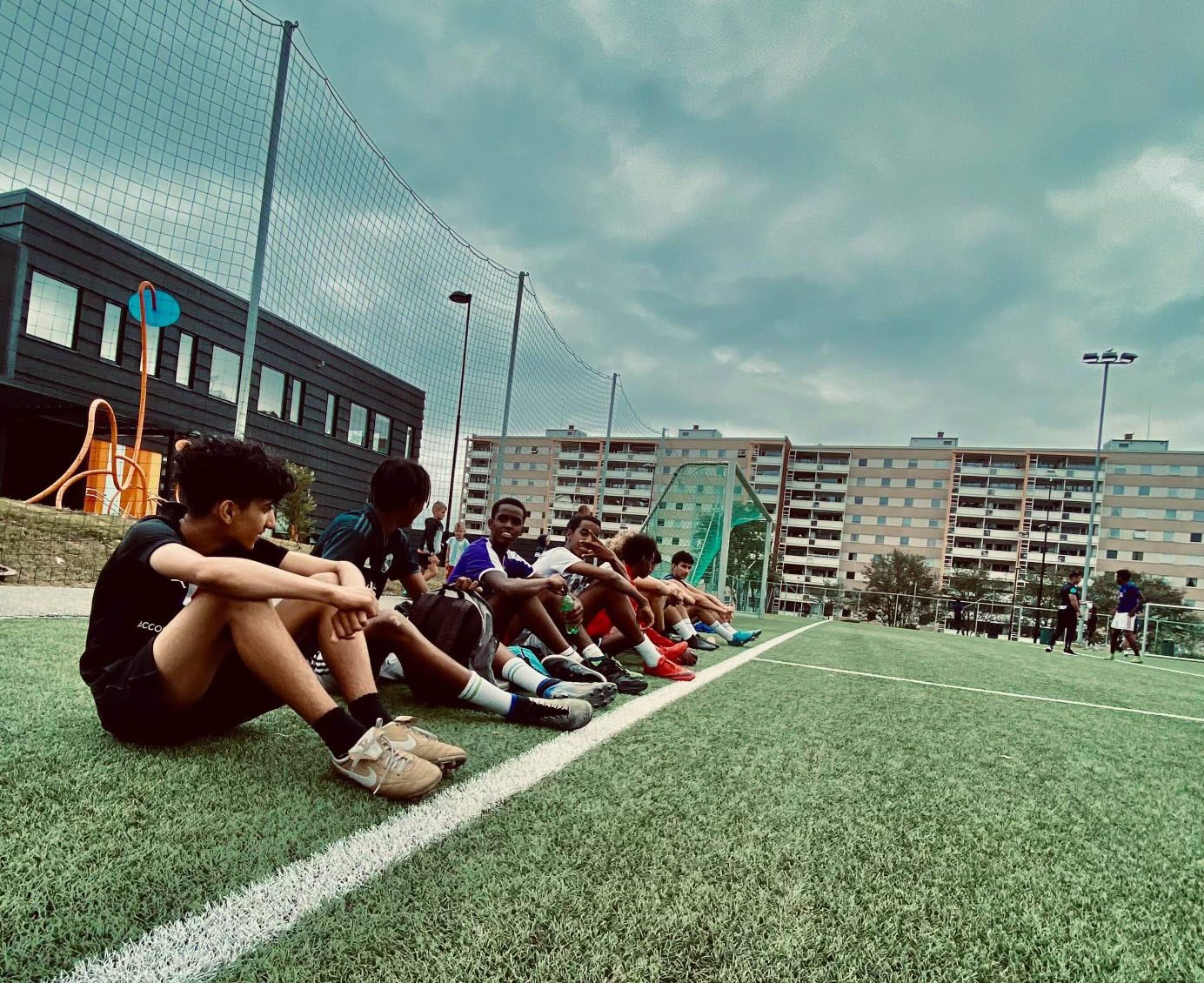 Ungdommer ved en fotballbane.